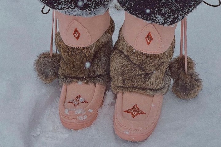 Person in snow wearing pink boots with fur trim and embroidered designs.