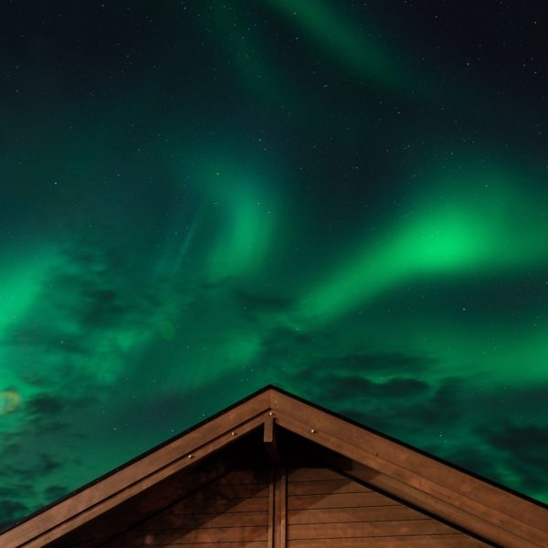 Aurora borealis glowing over snow-covered house roof near Fairbanks Alaska