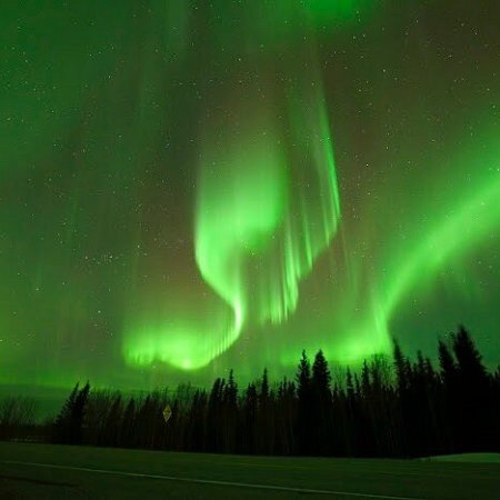 Bright green aurora sweeping across mountain silhouette in Fairbanks Alaska