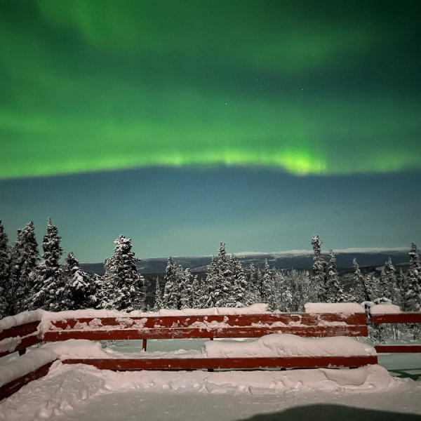 Bright northern lights sweeping over viewing platform near Fairbanks Alaska