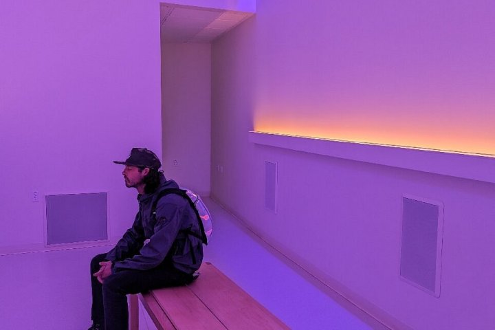 Person sitting on a bench in a purple-lit room with colorful corner lights.