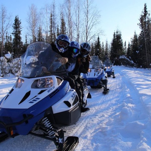 A man riding skis down a snow covered ski snowmobile