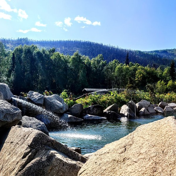 Rocky mountain with trees in background and water in foreground near Fairbanks Alaska