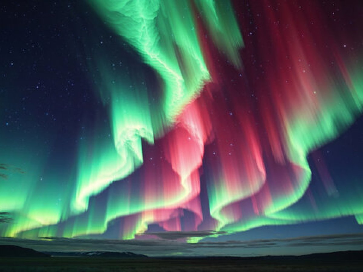 Vibrant green and red aurora borealis lights up the night sky over a dark landscape.