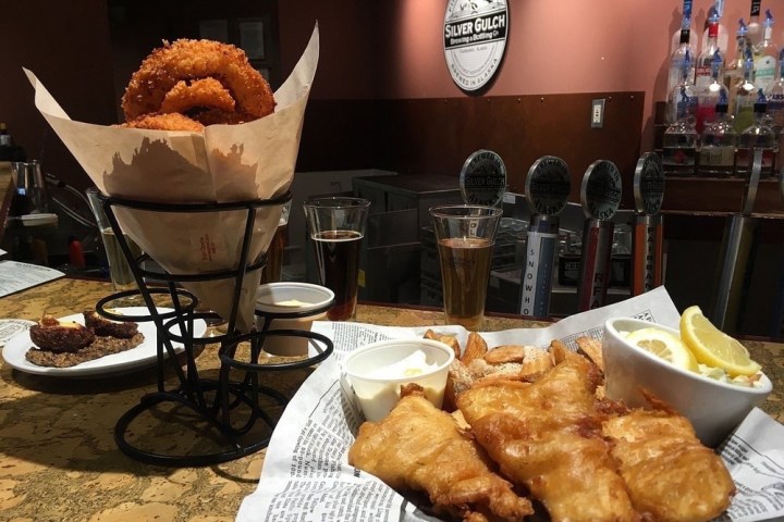 Bar counter with onion rings, fish and chips, drinks, and Silver Gulch Brewing sign in background.