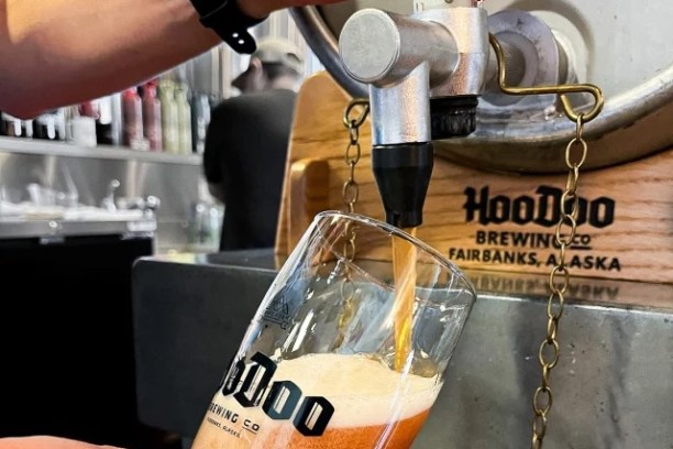 Person pouring beer into a glass from a tap at HooDoo Brewing Co.