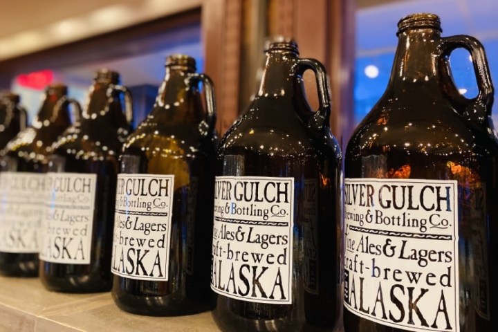 Line of dark glass beer growlers with Silver Gulch Brewing labels.