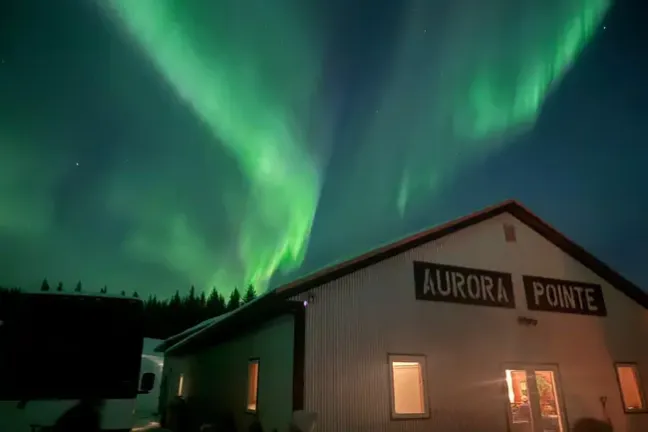 Northern lights over a building with 'Aurora Pointe' sign.