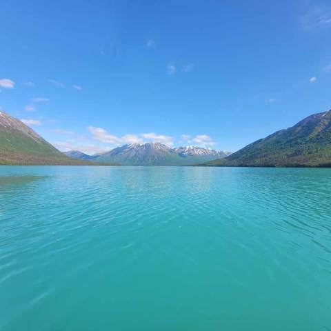 Turquoise lake surrounded by mountains under a clear blue sky.